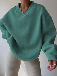 Detail of teal green V-neck loose sweatshirt with ribbed cuffs and drop shoulder