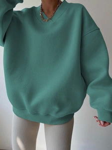 Detail of teal oversized V-neck sweatshirt featuring dropped shoulders and ribbed cuffs