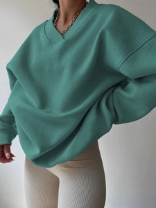 Detail of teal oversized V-neck sweatshirt featuring ribbed collar and soft fleece texture