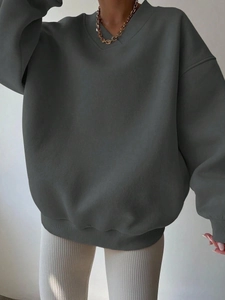Detail of dark grey oversized V-neck sweatshirt featuring ribbed cuffs and soft cotton texture