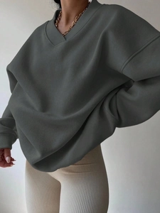 Detail of loose dark green V-neck sweatshirt with ribbed cuffs and drop shoulder