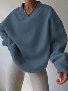 Detailed view of dust blue oversized sweatshirt with overlapping V-neck and ribbed cuffs