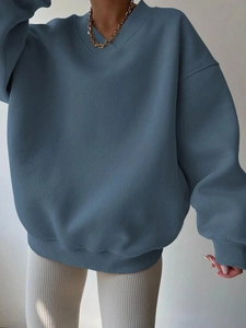 Detail of oversized misty blue V-neck sweatshirt featuring ribbed cuffs and soft fleece texture