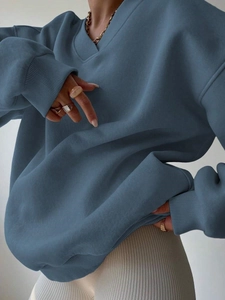 Detailed macro view of the blue oversized sweatshirt fabric texture and ribbed cuff design