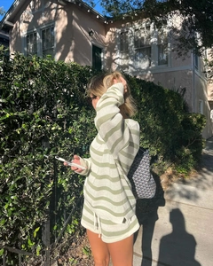Dettaglio della maglia del set a righe verde salvia indossato da una modella all'aperto