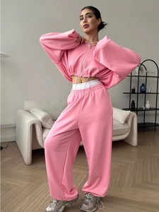 Detail of bright pink cropped hoodie with silver zipper and high-waisted wide-leg pants