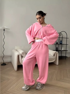 Pink lounge set featuring a cropped zip-up hoodie and wide-leg sweatpants in home setting