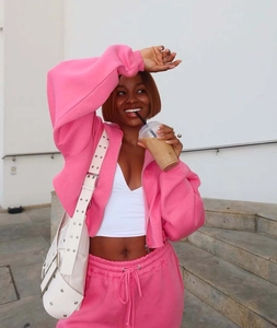 Detail of pink cropped zip-up hoodie and drawstring joggers set with a stylish white handbag