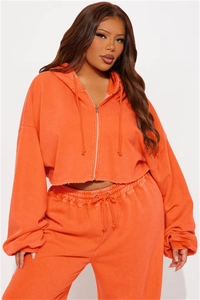 Detail of bright orange zip-up hoodie set with raw edge hem and drawstring waist pants