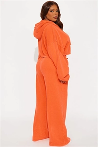 Detail of vibrant orange cropped hoodie and wide-leg sweatpants set with wash texture