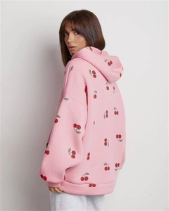 Detail of pink hoodie with red cherry print featuring soft fleece fabric and ribbed cuffs