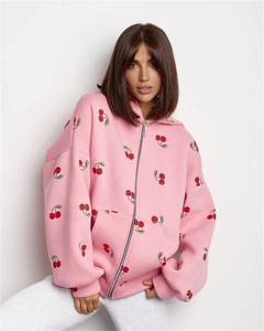 Close-up of pink oversized zip-up hoodie featuring detailed red cherry print and metal zipper