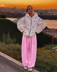 Detail of white hoodie with cherry embroidery and pink sweatpants at sunset scene