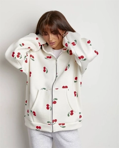 Detail of oversized white hoodie with vibrant red cherry print and metal zipper closure