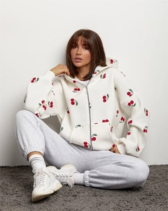 Close-up of white zip-up hoodie featuring red cherry prints and soft cotton texture