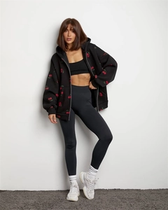 Detail view of black zip-up hoodie with cherry print and matching athletic wear
