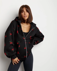 Detail of red cherry print on black oversized zip-up hoodie with metal zipper and pockets