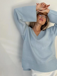 Dettaglio ravvicinato del maglione in maglia azzurro con scollo a V e polsini a costine