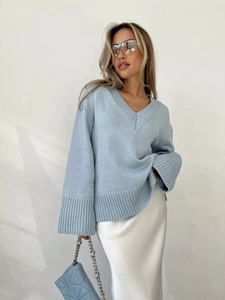 Dettaglio maglione azzurro scollo a V con polsini a costine e gonna di raso