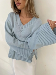 Dettaglio maglione azzurro oversize con scollo a V, spacco laterale e polsini a coste