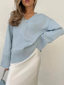Dettaglio del maglione in maglia azzurro con scollo a V e polsini a coste in primo piano