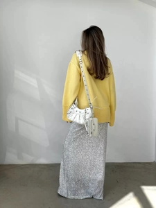 Dettaglio del maglione a maglia giallo scollo a V abbinato a una gonna lunga di paillettes