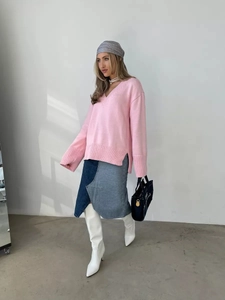 Dettaglio maglione rosa con scollo a V e spacco laterale abbinato a gonna in denim patchwork