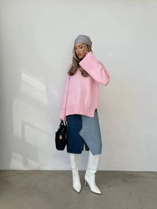 Dettaglio di maglione rosa con scollo a V a coste e gonna asimmetrica in denim patchwork