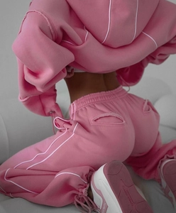Detail of pink hoodie set featuring white piping and drawstring cuff trousers