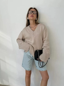Dettaglio maglione oversize beige con scollo a V e polsini a costine spesse