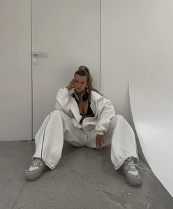 Detail view of white oversized hoodie and wide-leg jogger pants with black side stripes