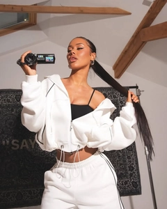 Detail of white two-piece sweatsuit with black piping, hoodie, and matching joggers