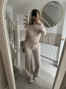 Detail of beige knitted tracksuit showing zip-up cardigan and high-waist drawstring pants