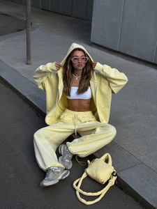 Detalle del conjunto de sudadera con capucha amarilla y pantalones de pierna ancha