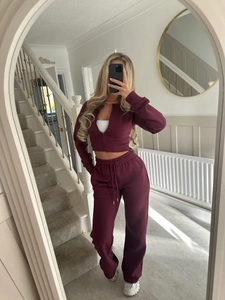 Detail of burgundy ribbed knit tracksuit featuring a zip-up sweatshirt and wide-leg trousers