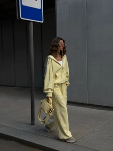 Detalle de conjunto de sudadera amarillo claro y pantalón ancho con bolso
