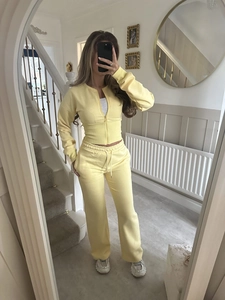 Detail view of a pale yellow two-piece knit set featuring a zip-up hoodie and wide-leg pants
