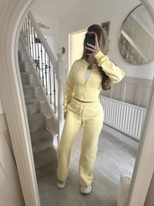 Detail of light yellow knit zip-up hoodie and matching straight pants in a home setting