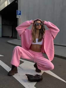 Detalle de sudadera con capucha rosa y pantalón deportivo en tejido de punto grueso