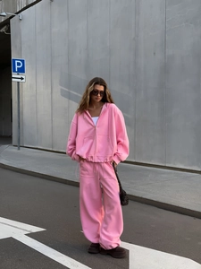 Detalle de conjunto rosa con sudadera con capucha y cremallera y pantalones anchos
