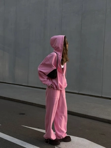 Detalle de sudadera rosa con cremallera metálica y pantalones deportivos anchos a juego