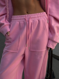 Detalle de sudadera con capucha rosa y pantalones anchos con cordón y bolsillos