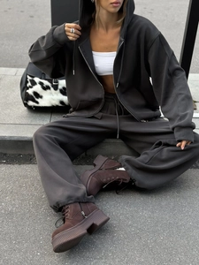 Detalle de sudadera gris con cremallera y pantalones anchos a juego en estilo urbano
