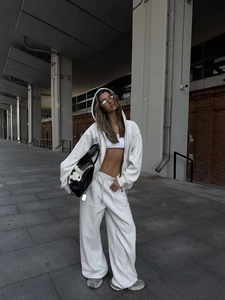 Detalle de un conjunto de sudadera con capucha y pantalón ancho gris claro estilo urbano