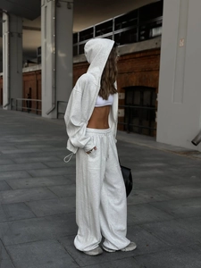 Detalle del conjunto de sudadera gris claro y pantalón ancho con cordón y bolsillos