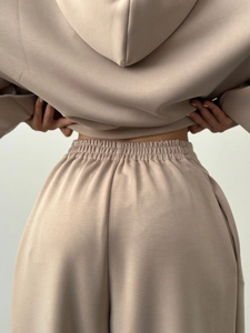 Détail de la taille élastique haute et du drapé du tissu premium sur l'ensemble beige