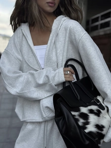Detalle de conjunto gris claro con sudadera con capucha y cremallera y pantalón ancho