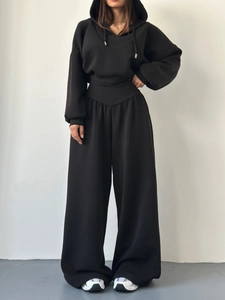 Détail du survêtement à capuche noir avec cordon et texture du pantalon large