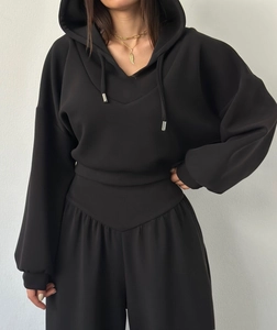 Détail du sweat à capuche noir et du pantalon taille haute avec coupe en V unique