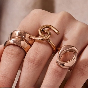 Close-up of three minimalist rose gold geometric rings worn on model fingers